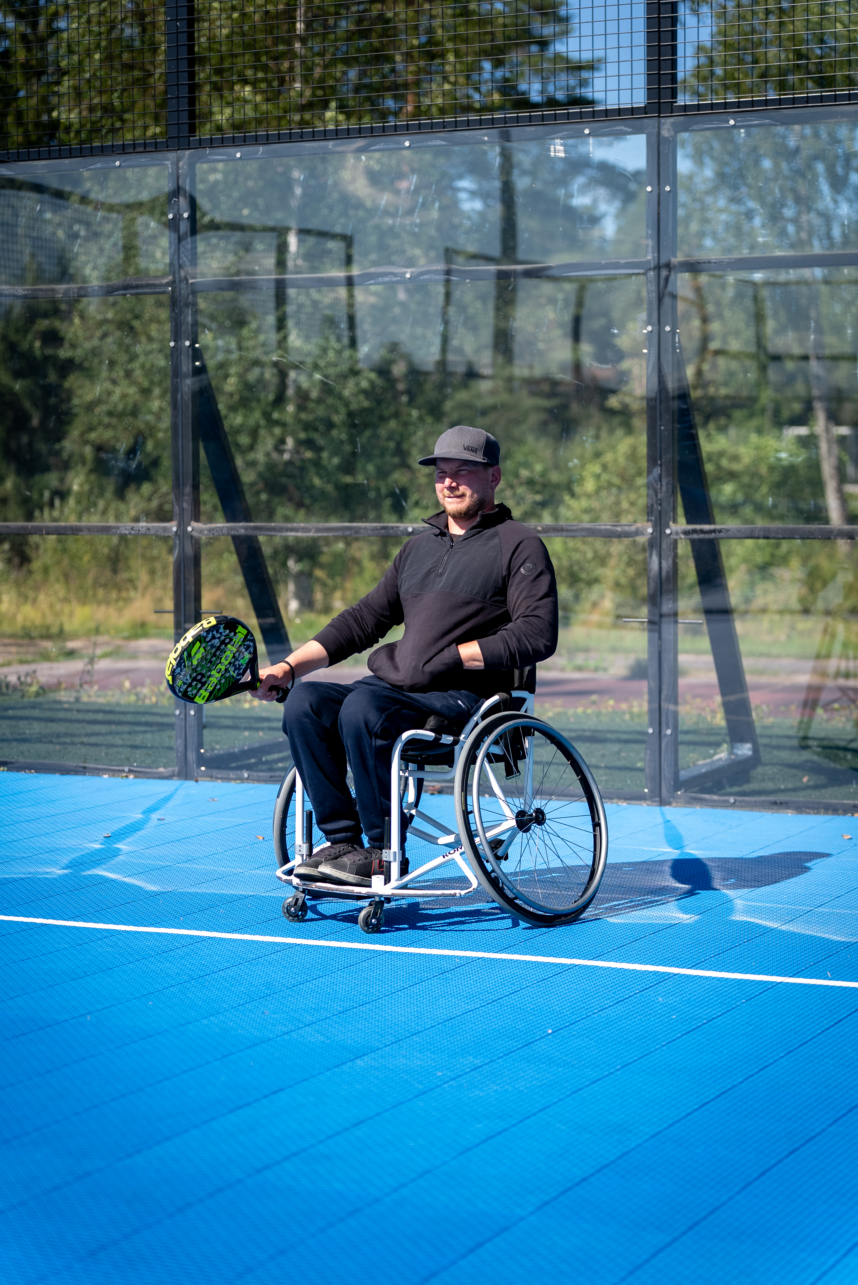 Kuvassa henkilö pelaa padelia pyörätuolista käsin